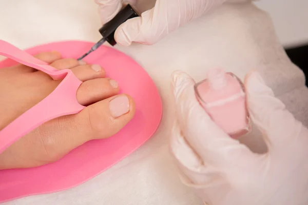Close-up Of A Beautician Applying Nail Varnish To Woman's Feet