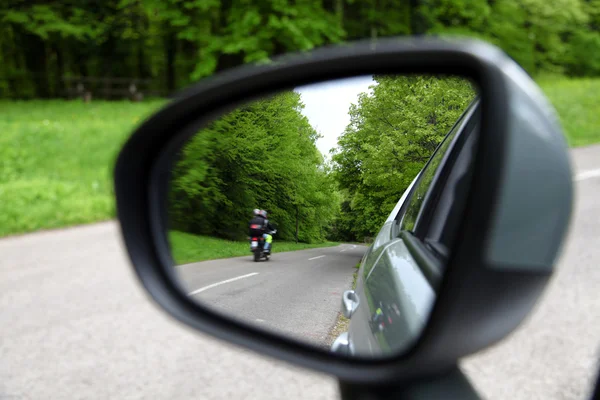 Forest road reflection,  rearview car driving mirror view green