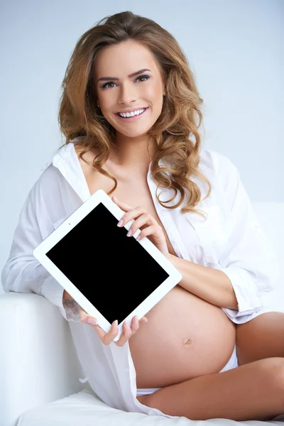 Beautiful pregnant woman with tablet