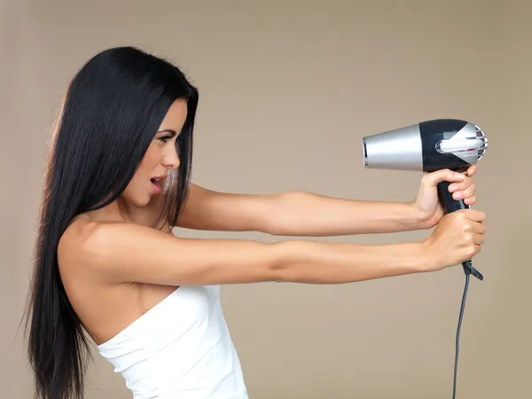 Playful woman having fun with a hairdryer