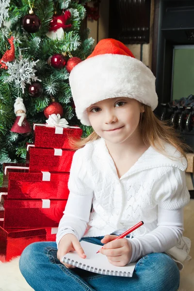 Funny girl in Santa hat writes letter to Santa