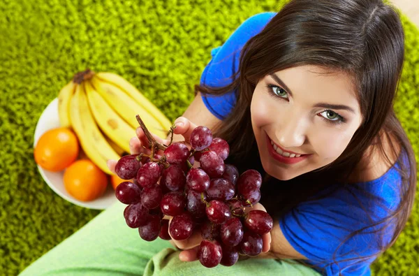 Woman seating on floor with fruits.