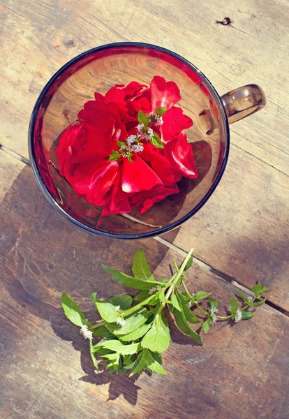 The bowl with rose petals and mint rose and mint on old wooden b