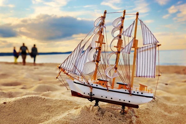 Ship model on summer beach at sunset