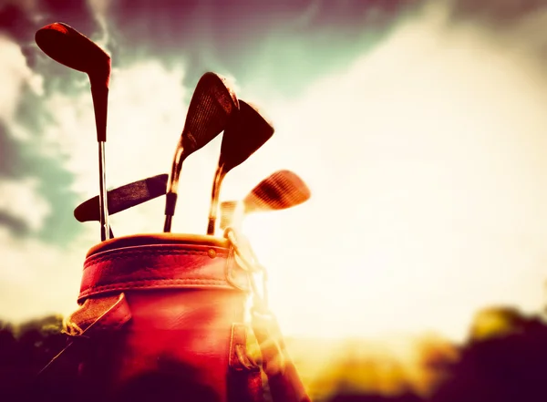 Golf clubs in a leather baggage in vintage, retro style at sunset