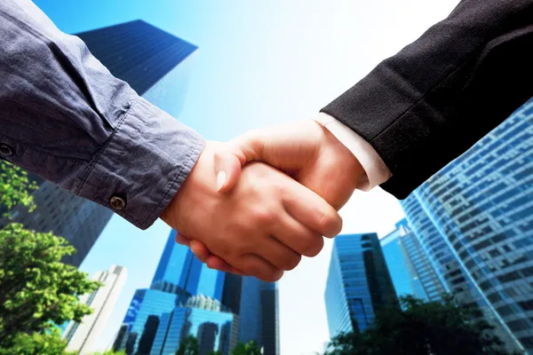 Business handshake, skyscrapers background