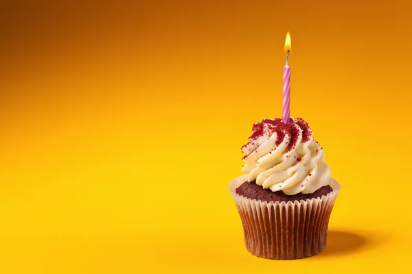 Chocolate cupcake with candle isolated on orange background with
