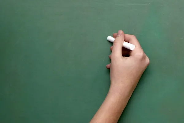 A man holds a piece of chalk, as if ready to write on a chalkboa