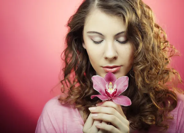 Woman with orchid flower over pink background