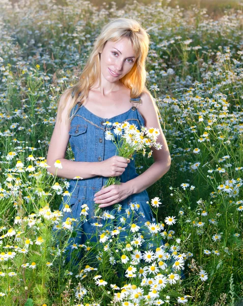The beautiful happy young woman in the field of camomile