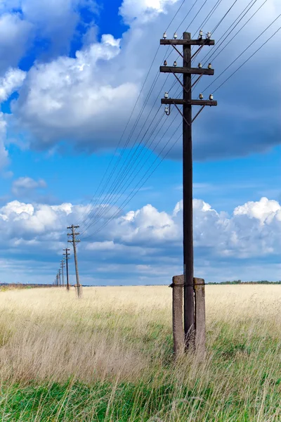 Old wooden poles - the line of electricity transmissions - in the field