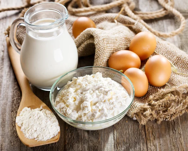 Milk, cottage cheese, eggs and flour on wooden table