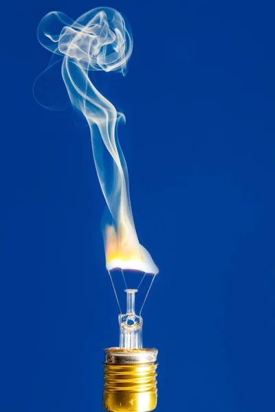 Broken light bulb burn out with flame on blue
