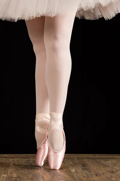 A ballet dancer standing on toes on wood floor