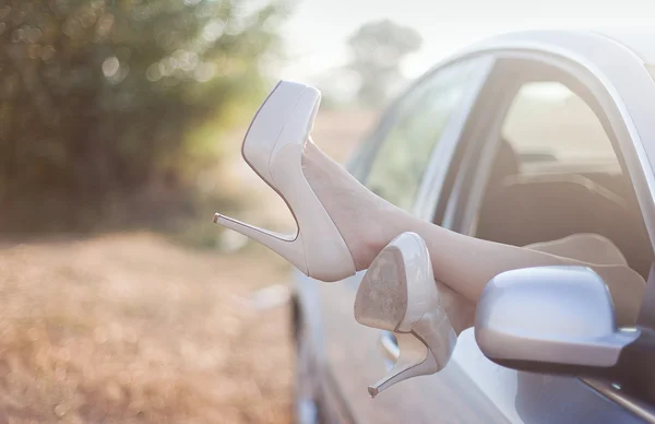 Sexy woman legs on high heels out the windows in car