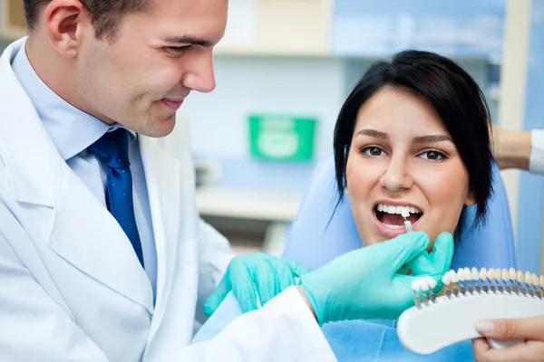 Dentist examining a whiteness of teeth of a patient