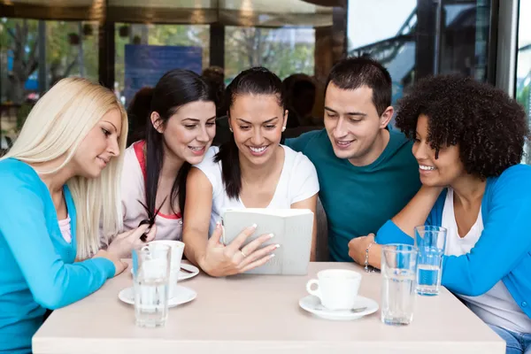 Teens using their digital tablet in a cafe