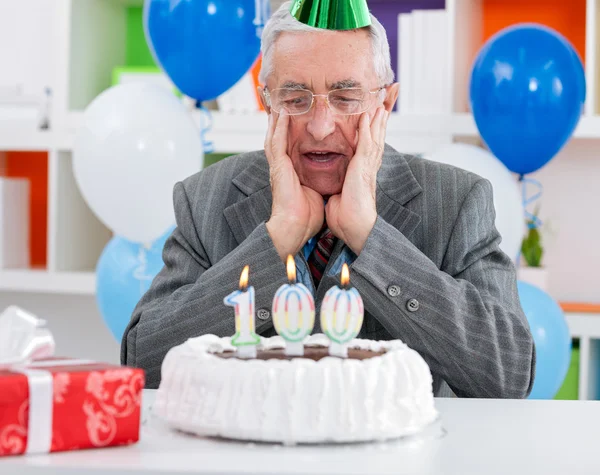 Surprised senior man looking at birthday cake
