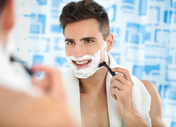 Happy laughing man shaving his face