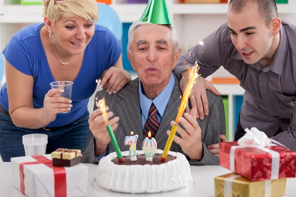 Senior man blowing candles