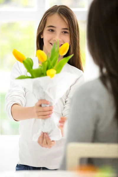 Cute girl giving flowers her mom