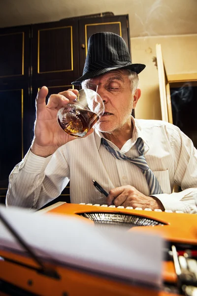 Retro Senior Man writer with a glass of whiskey