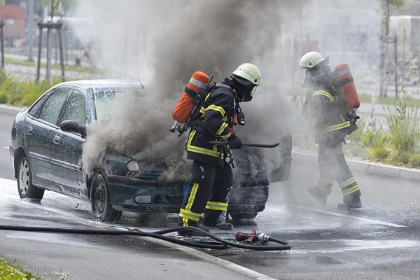 Firefighters are putting out a burning car