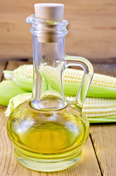 Corn oil in a carafe with corncobs on board