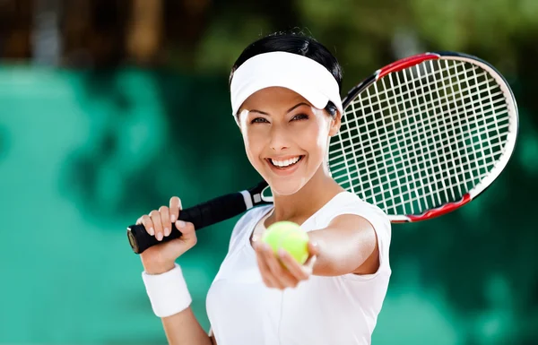 Woman serves tennis ball