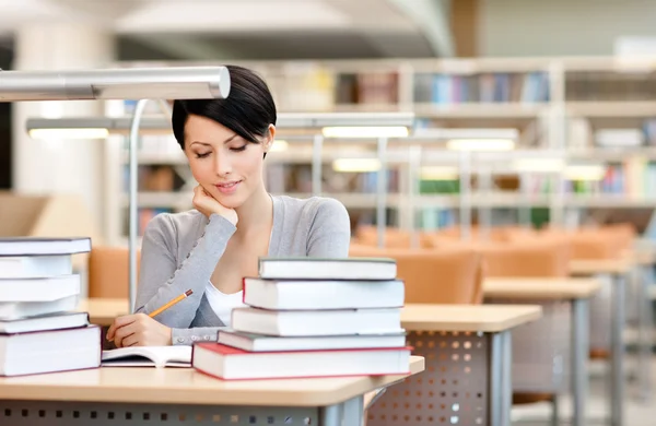 Beautiful student studies with piles of books — Stock Photo #13192403