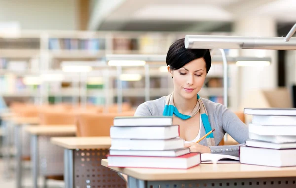 Young female studies with piles of books