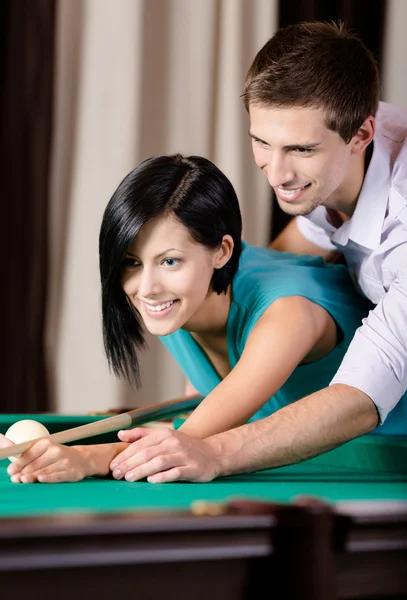 Man teaching young woman to play billiards