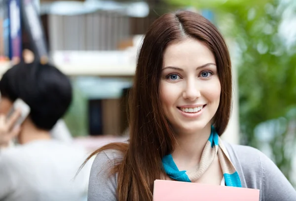 Beautiful woman student at the library against bookshelves