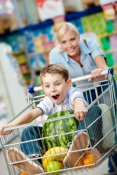 Little boy sits in the shopping trolley with watermelon
