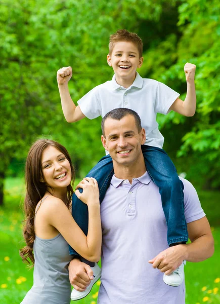 Happy family of three. Daddy keeps son on shoulders