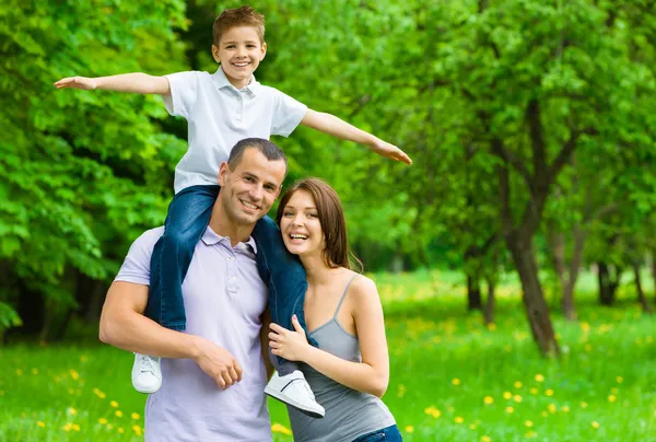 Happy family of three. Father keeps son on shoulders