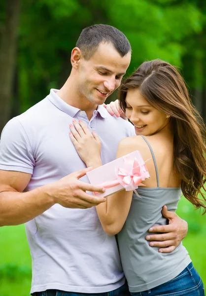 Man gives present to woman in park
