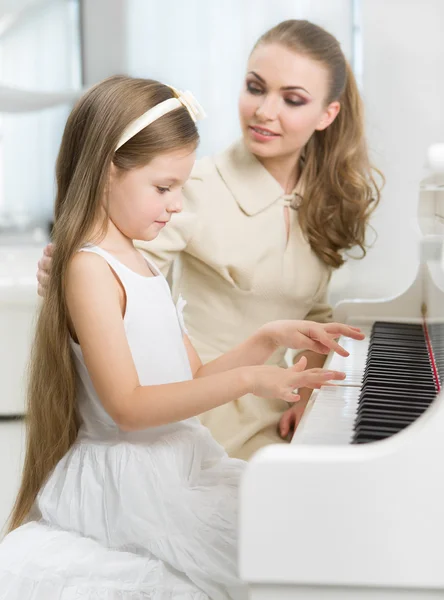 Tutor teaches little child to play piano