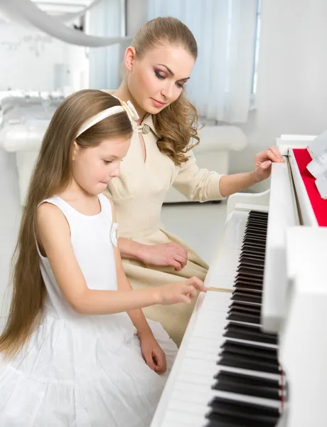 Teacher teaches little girl to play piano