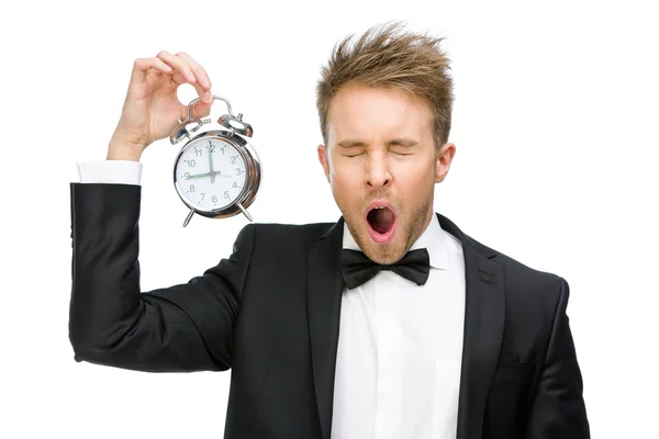 Businessman yawns keeping alarm clock