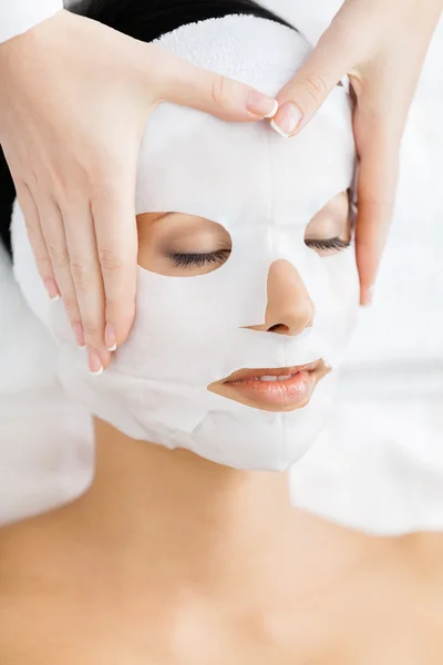 Hands of therapist apply mask to woman face
