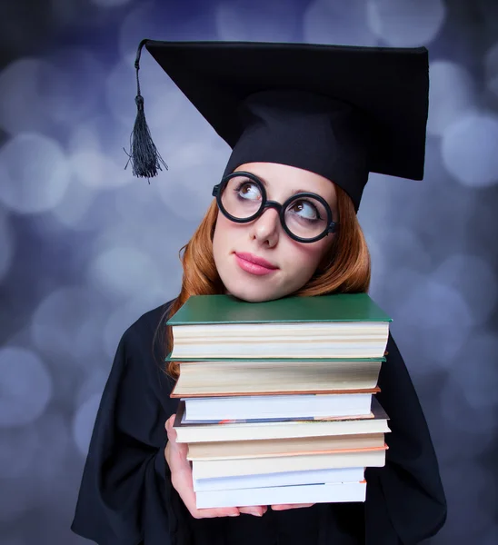 Graduating student girl in an academic gown with books
