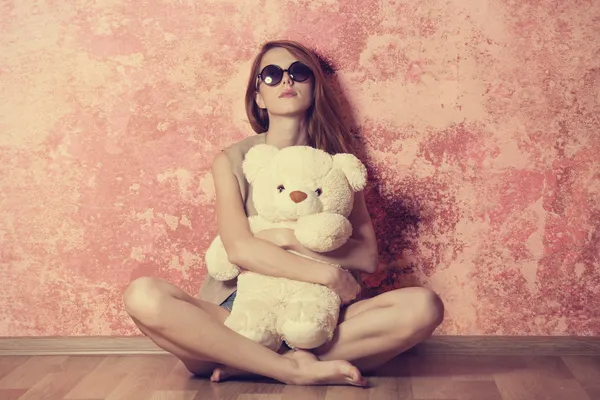 Sad grunge girl near wall with teddy bear