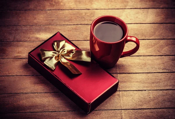 Gift and cup of coffee on wooden table