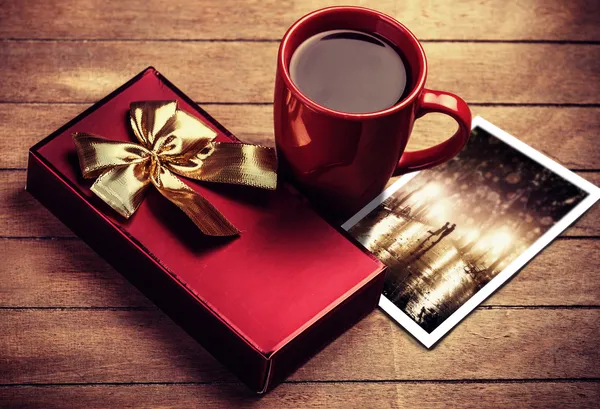 Gift and cup of coffee on wooden table