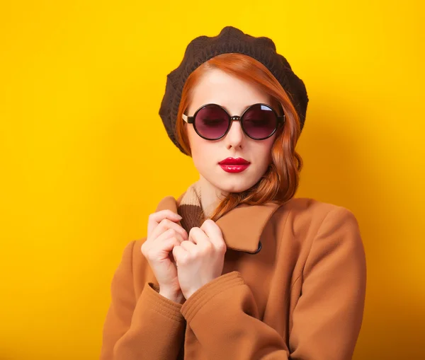 Redhead women in beret on yellow background.