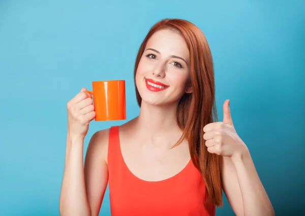 Redhead women with cup on blue background.