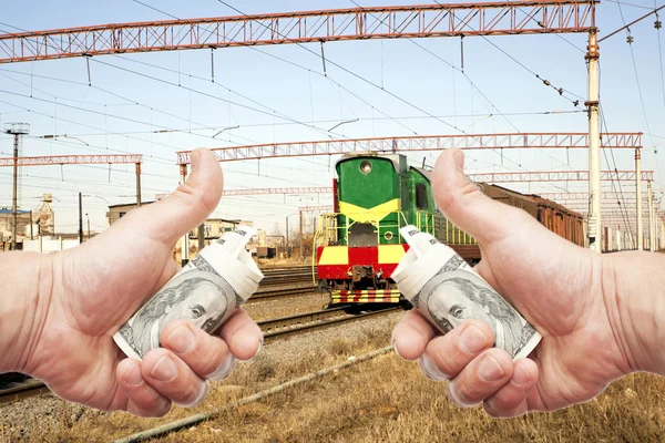 Hands with notes of US dollars against the train on the railroa