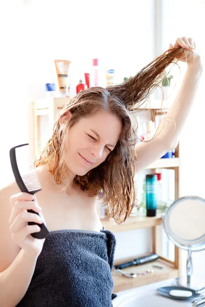 Young girl taking care of her hairs in a bathroom