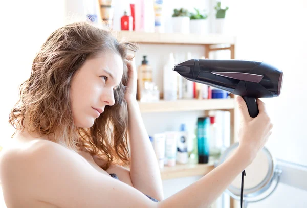 Young girl taking care of her hairs in a bathroom